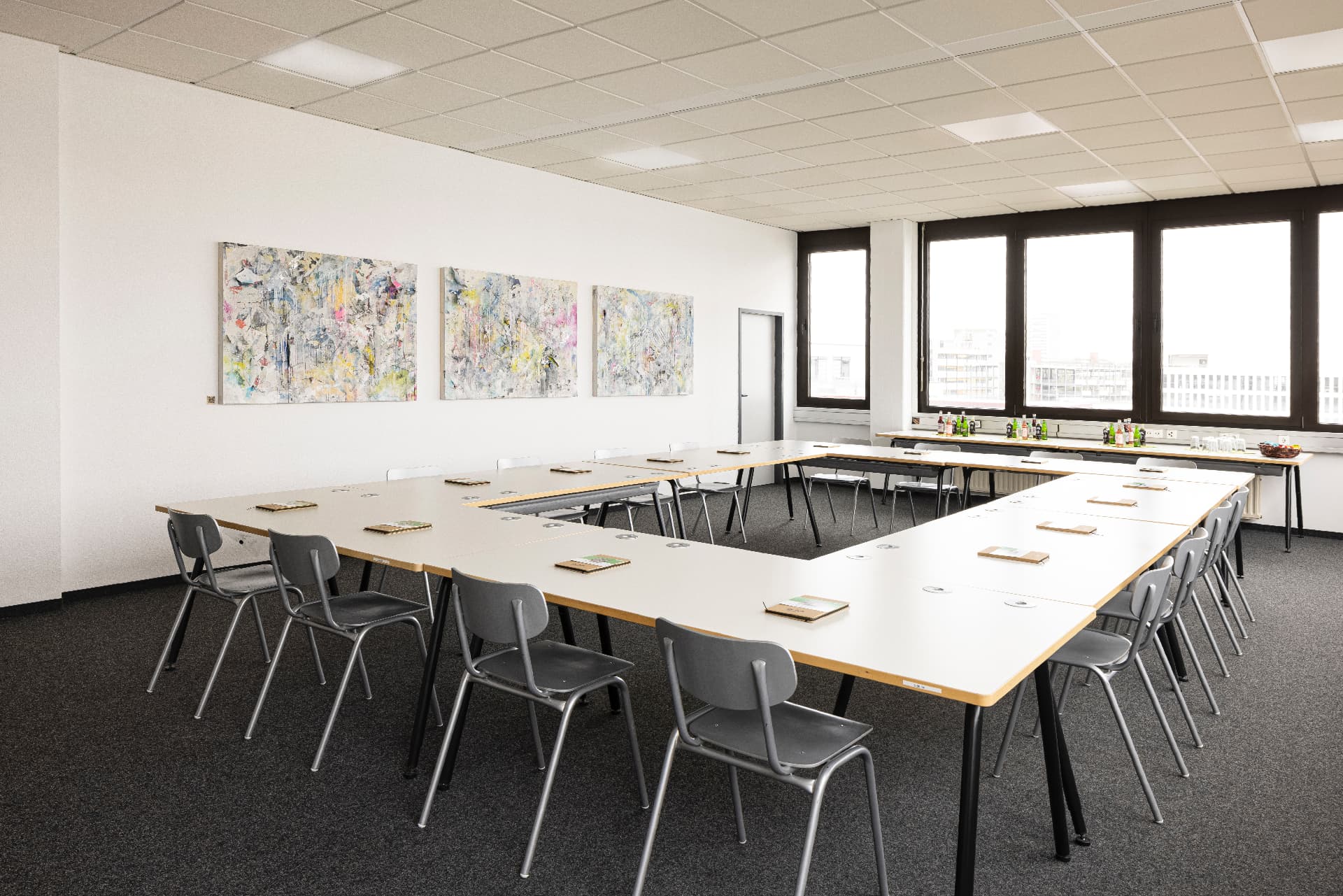 Conference Room with U-shaped table setup, grey chairs and art on the wall