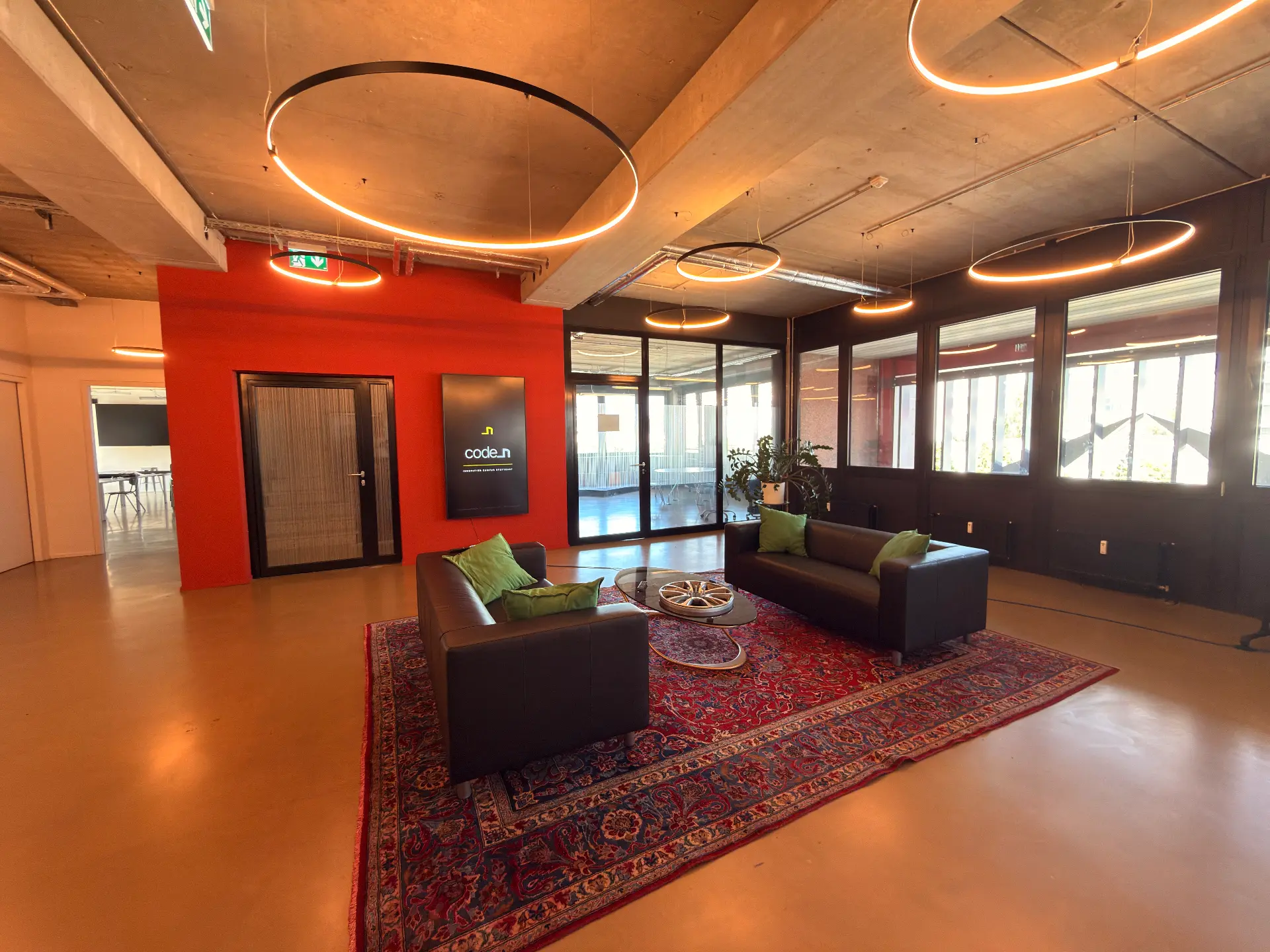 Second floor foyer with red wall, code_n sign, leather sofas and ring lights