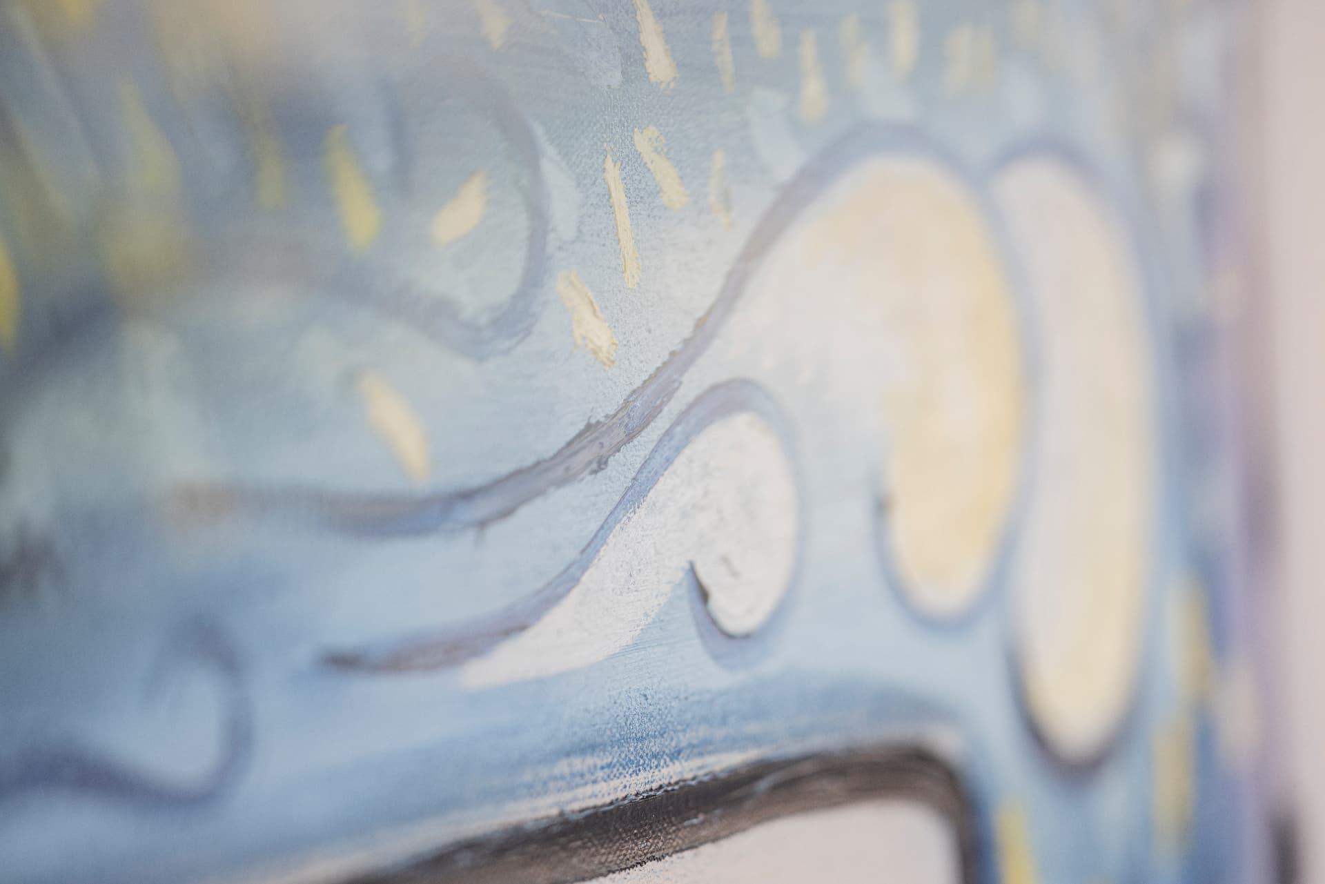 Close-up of a light blue painting with curved lines and yellow brushstrokes